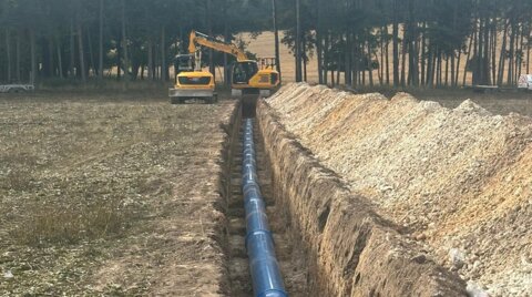 Long trench excavated across farmland with blue Molecor MoPVC pipe laid along the base
