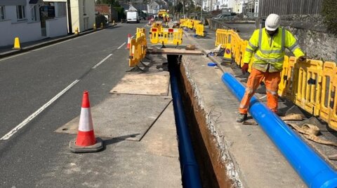 Blue Molecor MoPVC pipe positioned along a narrow trench during installation in a live residential street