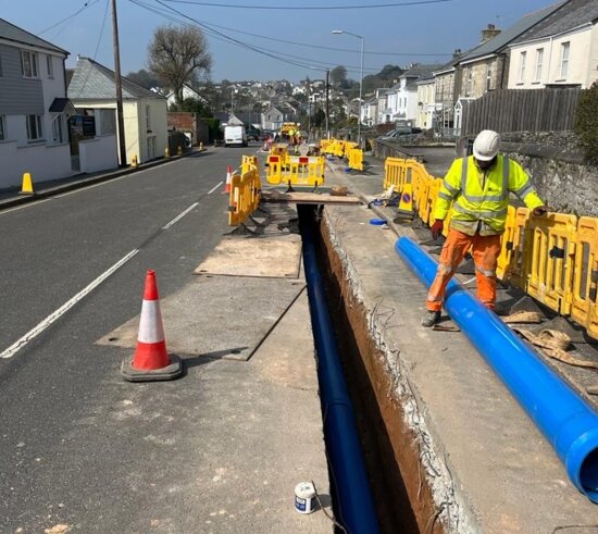 Blue Molecor MoPVC pipe positioned along a narrow trench during installation in a live residential street