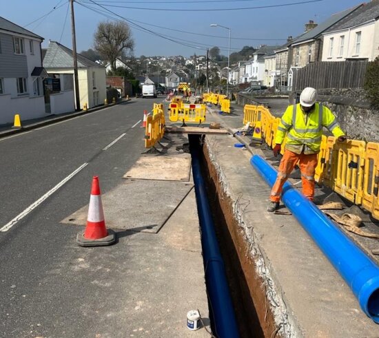 Blue Molecor MoPVC pipe positioned along a narrow trench during installation in a live residential street