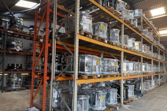 Rows of palletised pipeline fittings wrapped and stored on multi level racking inside a large warehouse with high stock availability