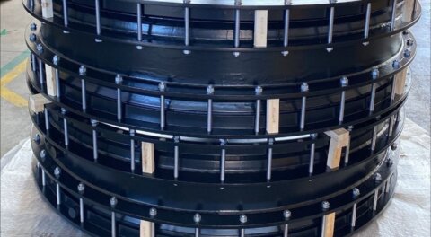 Worker standing inside a DN1600 Nova Siria coupling in a warehouse, illustrating the scale and size of the large-diameter fitting