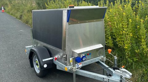 Portable trailer-mounted unit parked on a roadside, with integrated control panel and stabilising legs deployed