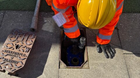Engineer securing a Haldi hydrant safety clamp onto a live hydrant using an electric driver during installation