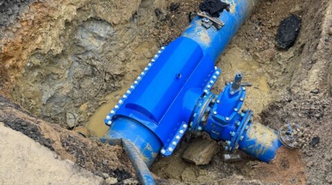Completed installation of an encapsulation collar sealing a previously leaking under-pressure tee on a water main