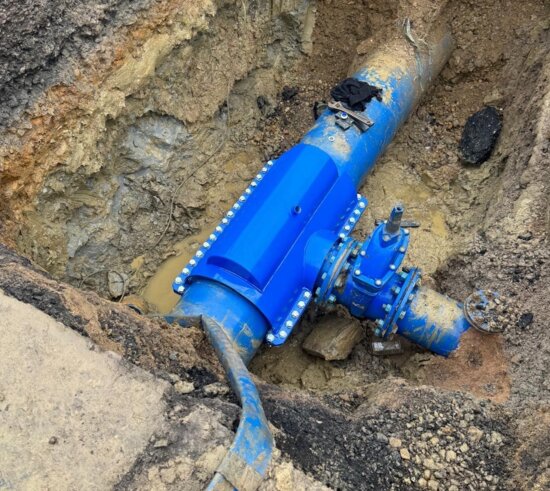 Completed installation of an encapsulation collar sealing a previously leaking under-pressure tee on a water main