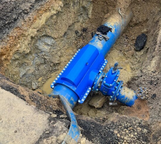 Completed installation of an encapsulation collar sealing a previously leaking under-pressure tee on a water main