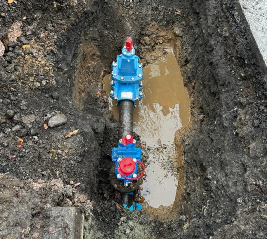 Overhead view of an excavation showing a newly installed EZ valve connected to a water main