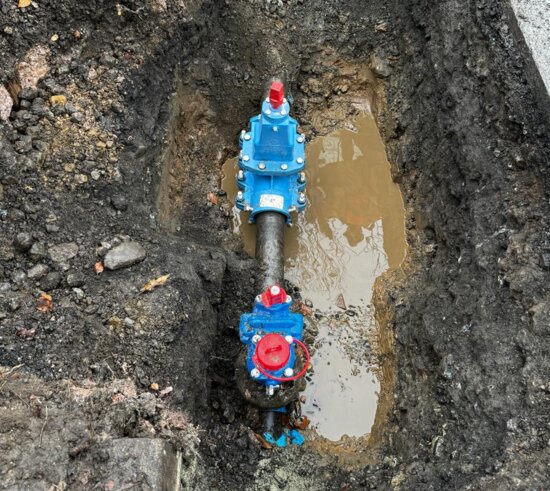 Overhead view of an excavation showing a newly installed EZ valve connected to a water main