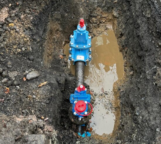 Overhead view of an excavation showing a newly installed EZ valve connected to a water main