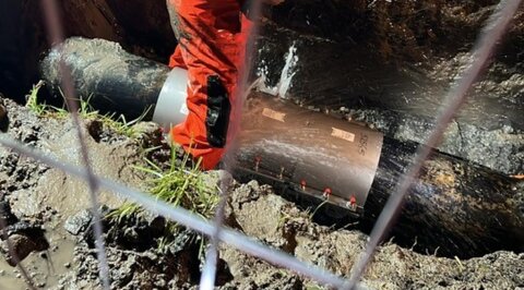 Live water network showing a leaking repair clamp within an excavation prior to repair works being carried out