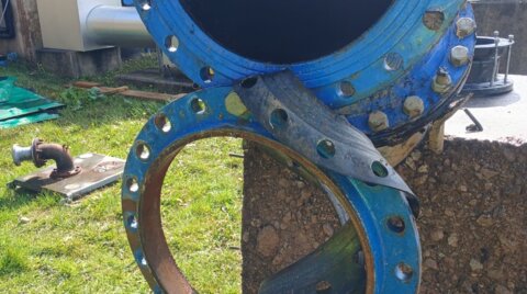 Damaged large-diameter pipeline section prior to replacement, showing failed flange joints removed during emergency repair works on a water network