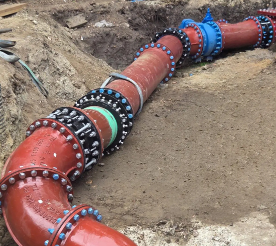 Bespoke ductile iron pipeline including flanged fittings and couplings installed in an excavated trench as part of a custom engineered solution