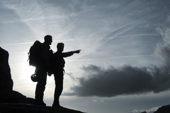 Hawle stands for partnership Two mountain climbers stand at the peak and look off into the distance