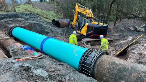 Wide view of pipeline installation showing the Multigrip end restraint coupling in place, with site operatives and excavation equipment