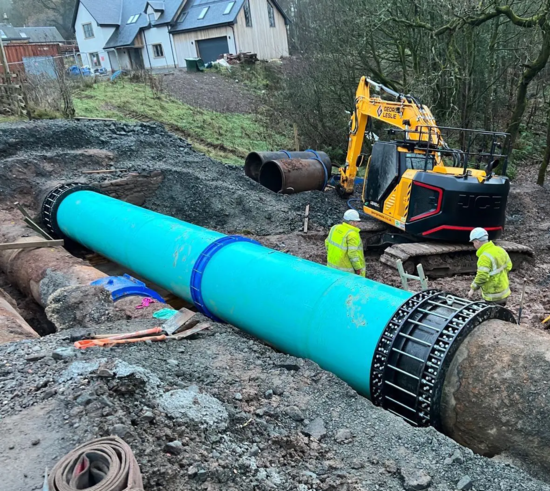 Wide view of pipeline installation showing the Multigrip end restraint coupling in place, with site operatives and excavation equipment