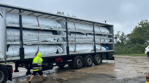 Articulated lorry delivering packaged Molecor MoPVC pipes to site, with lifting equipment positioned for unloading