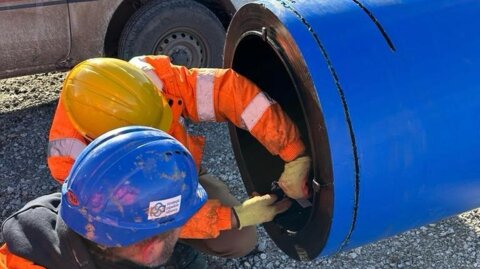 Two workers closely inspecting a large-diameter pipe during an on-site training session with the customer